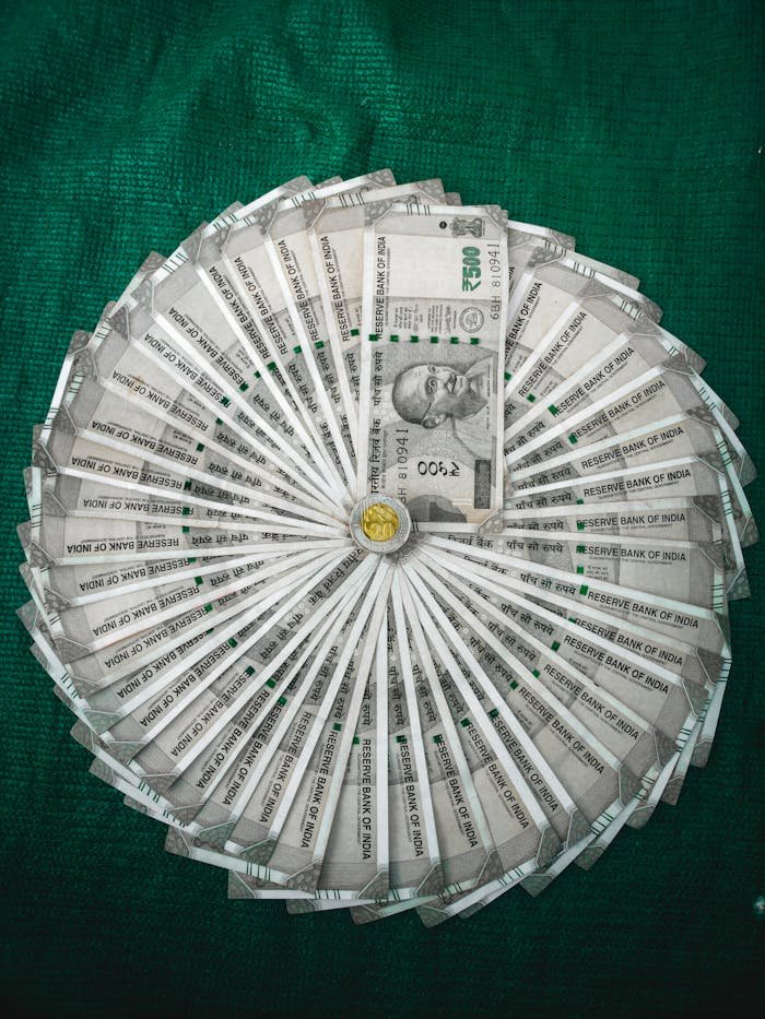 Top view of Indian Rupee notes arranged in a circular pattern on a green surface.
